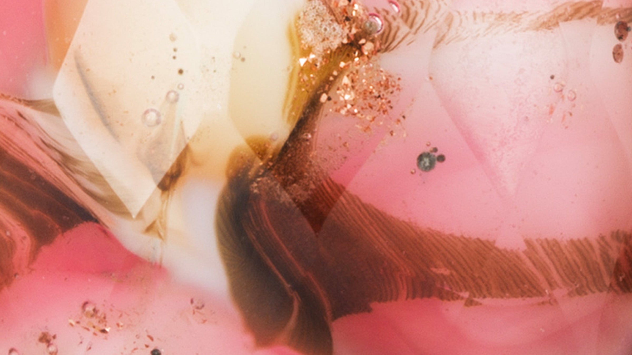 Nærbillede af Trollbeads Rubin Venskab. Blomsterblade i sart pink og rosenrøde nuancer iblandet guldglimmer flyder igennem denne facetterede glaskugle. 